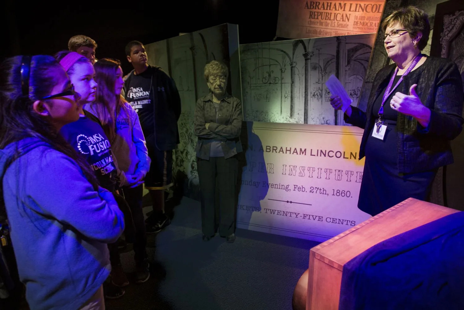 Students and a docent at an exhibit during a field trip.