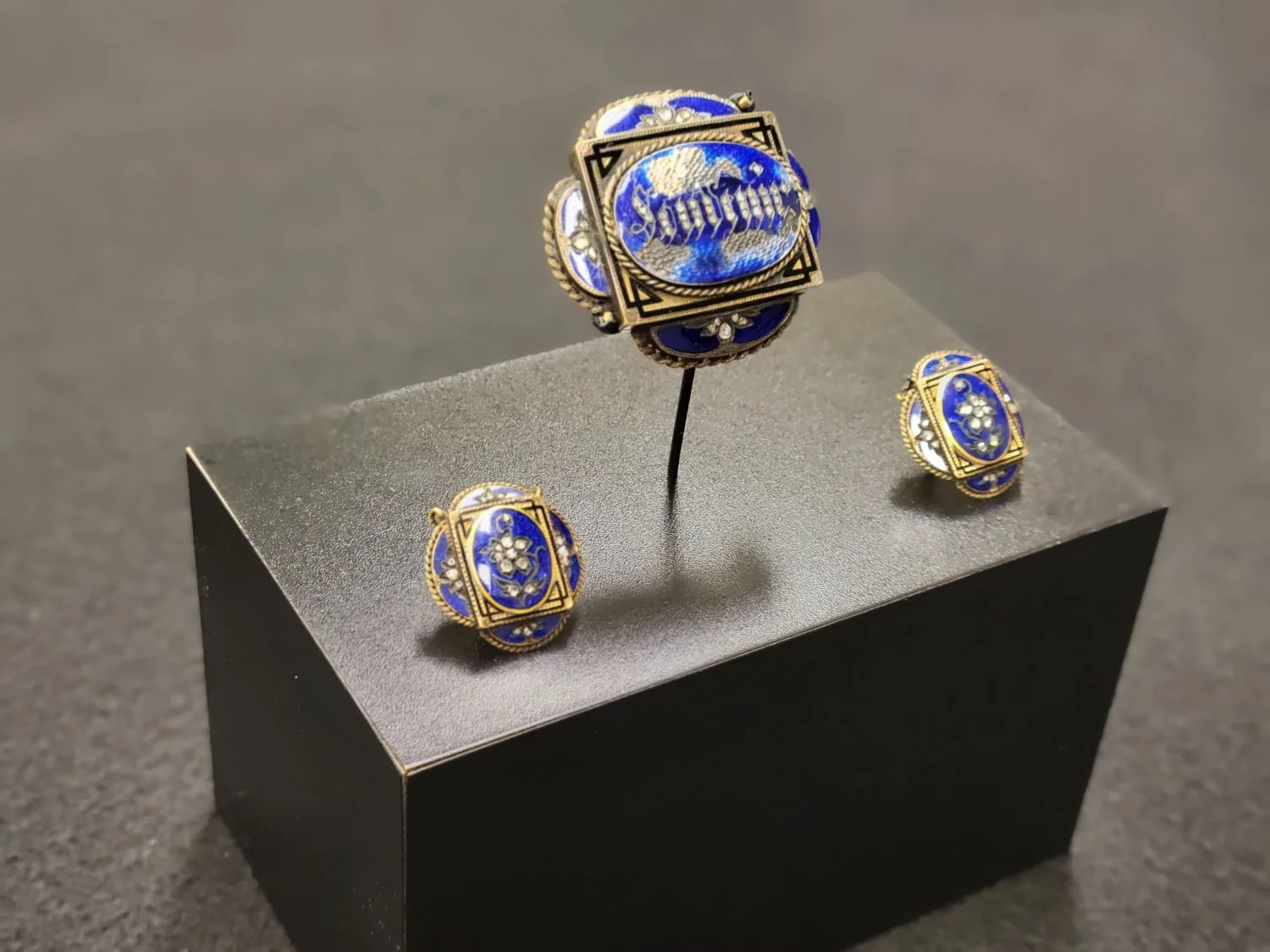 A pair of Mary Lincoln's gold and enamel cufflinks displayed on a black pedestal.