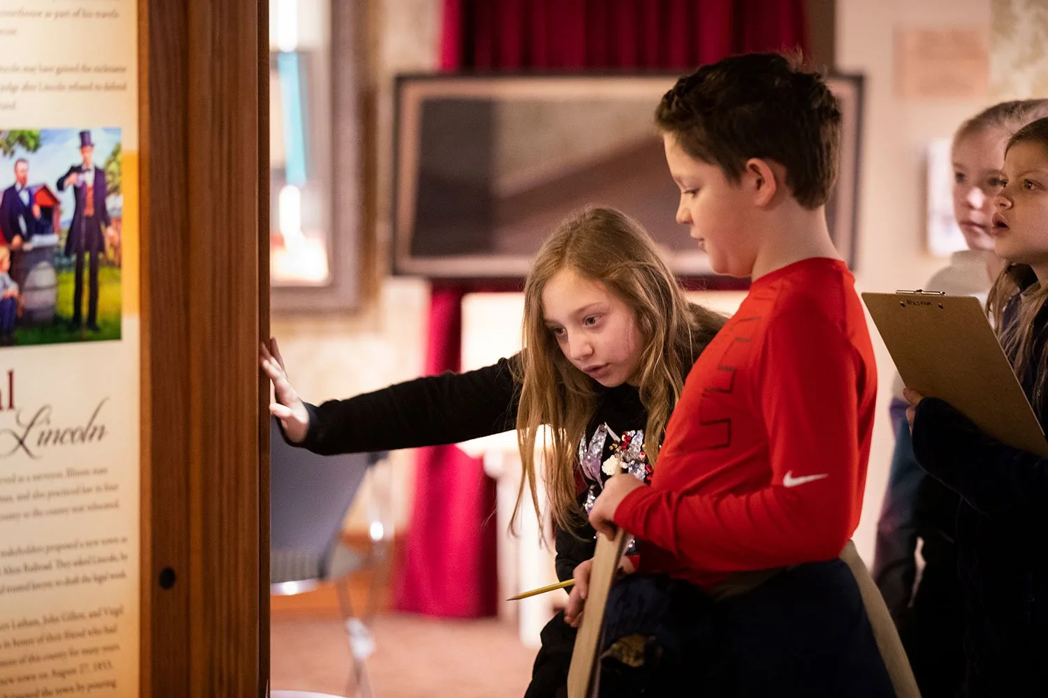 Children reading an exhibit panel with a guide.